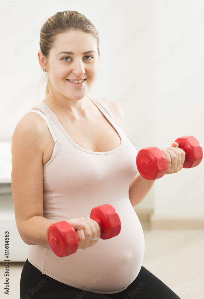 young pregnant woman exercising with weights at home young pregnant woman exercising with weights at home