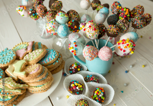 Decorated cake pops and cookies for Easter on wooden table