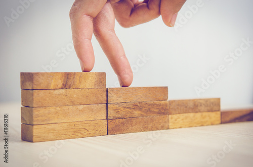 Woman hand walking his fingers up wooden steps on the way to success and aspiration. Business occupation
