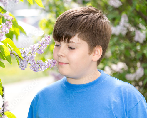 boy smelling a lilac flowers in park