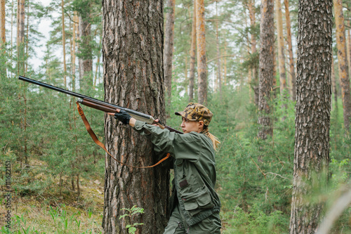 Woman hunter with a gun. Hunting in the woods.