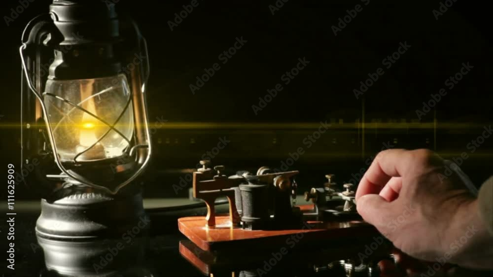 The flame from an oil latern throws a lens flare across a telegrapher sending a telegraph message.