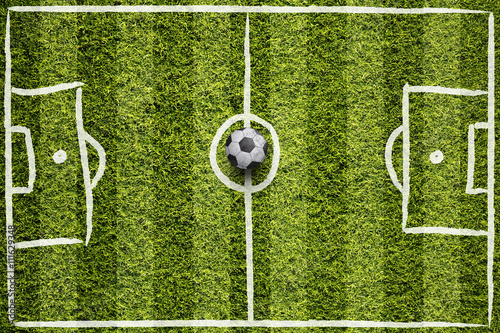 Hand drawn soccer field lines or football field lines with illustrated soccer ball on sunny green grass background. 