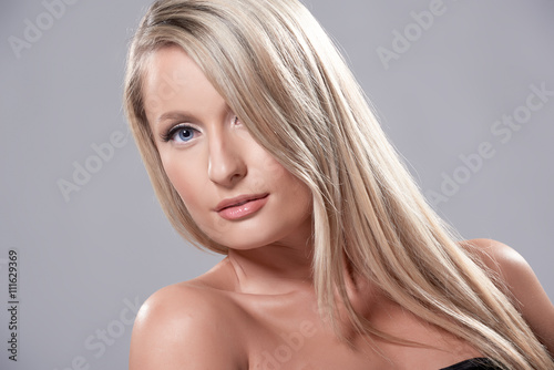 Portrait of beautiful blond model with blue eyes, on grey background