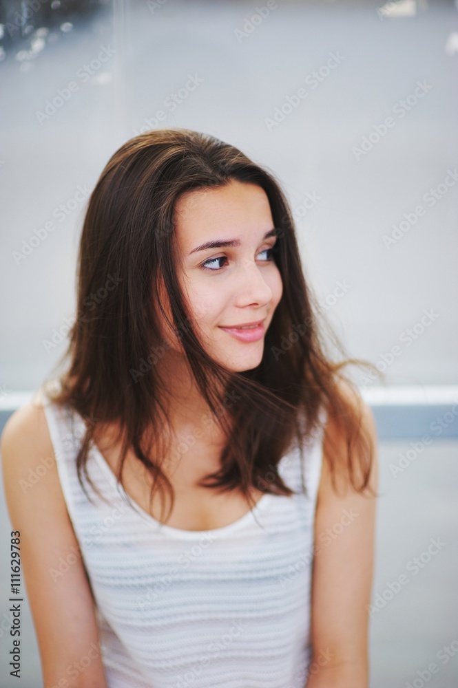 teenager girl in a white shirt smiles sweetly. Her hair fluttering in the wind. teenager girl in a white shirt smiles sweetly. Her hair fluttering in the wind.