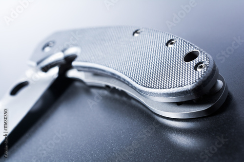 Close Up Of A Lying Half Opened Faint Military Knife On Dark Ground photo