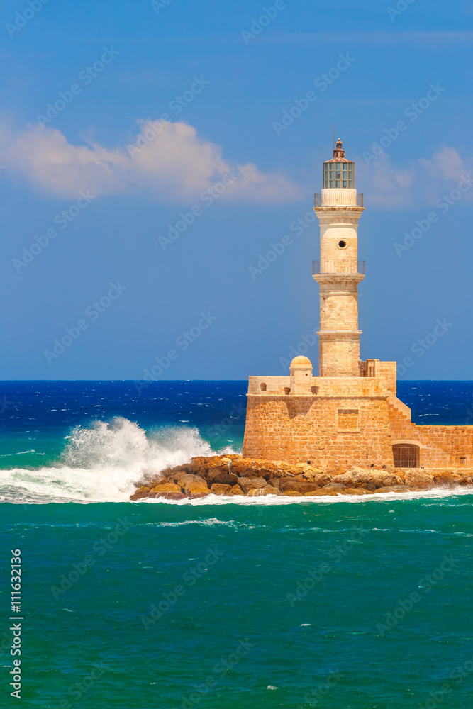 Waves beat against the lighthouse in old harbour of Chania in the summer sunny day, Crete, Greece