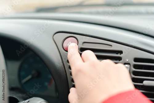 Young lady pressing emergency button on car sport dashboard.Closeup 