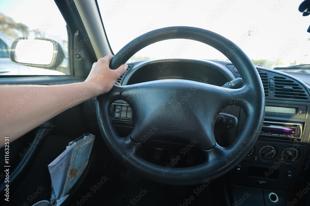 Female hand driver behind the wheel of a car, closeup 