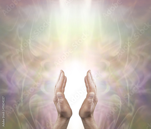 Pranic Healer sending distant healing - Male parallel hands with a white light behind on a soft ethereal misty muted color background and copy space