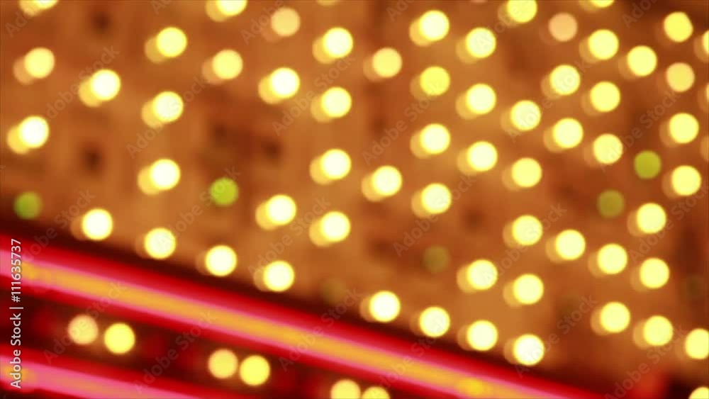 A close up of out of focus flashing  blinking  rhythmic lights of a large flamboyant sign.