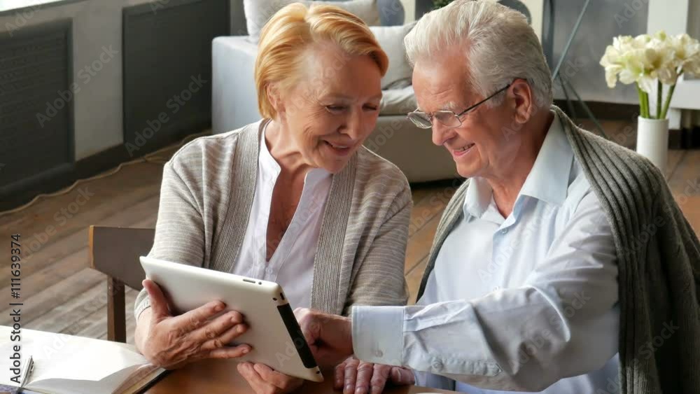 Senior couple websurfing on internet with tablet. Happy elderly man and woman using tablet computer