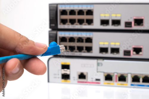 Close-up Hand holding ethernet cable on network POE switches background. Selective focus