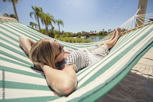 Woman sunbathing, relaxing and resting in a hammock while staying at a tropical resort on vacation photo