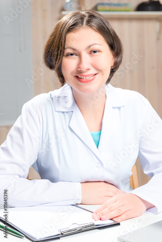 smiling woman doctor in a white medical dressing gown