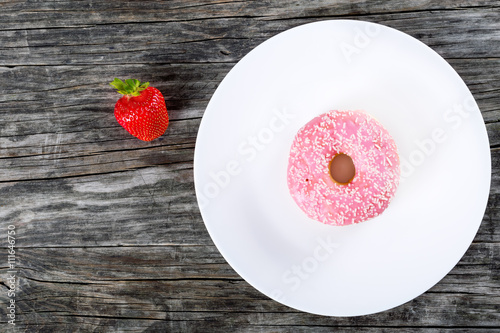 Donut with Strawberry Icing on white dish. top view