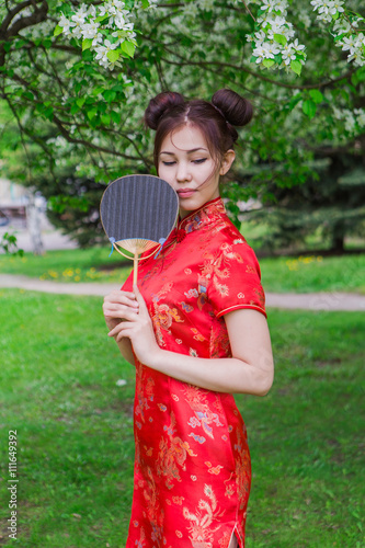 Beautiful asian girl with fan in traditional chinese red dress.