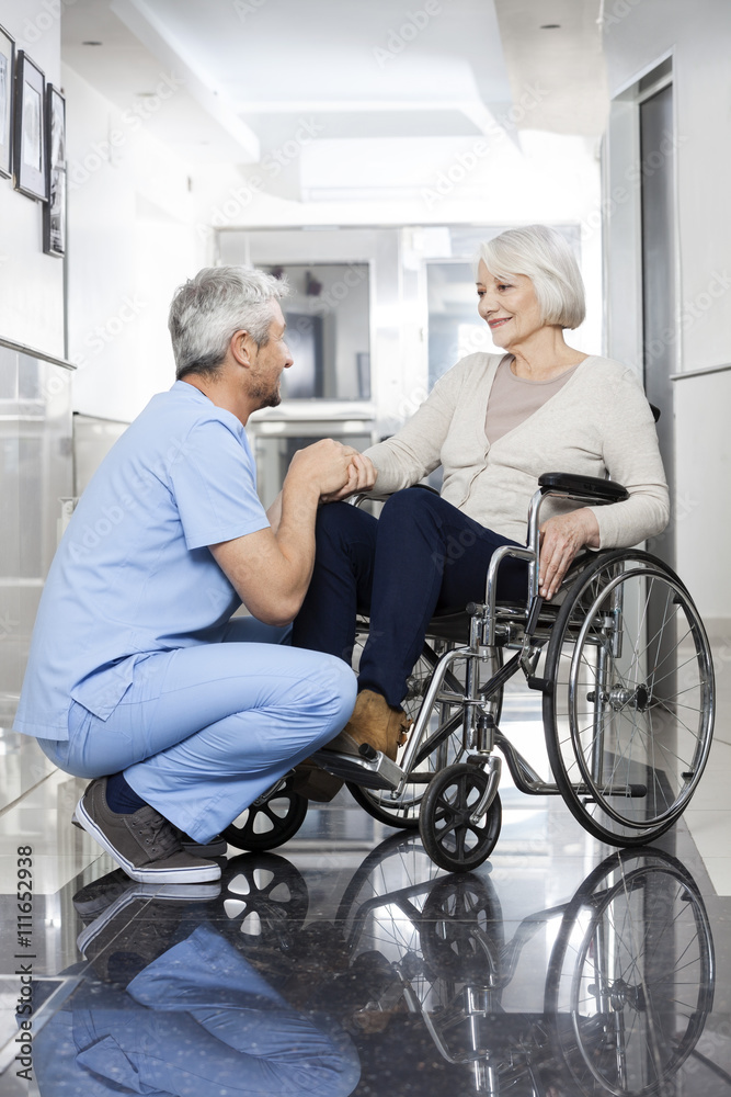 Physiotherapist Holding Senior Patient's Hand On Wheelchair