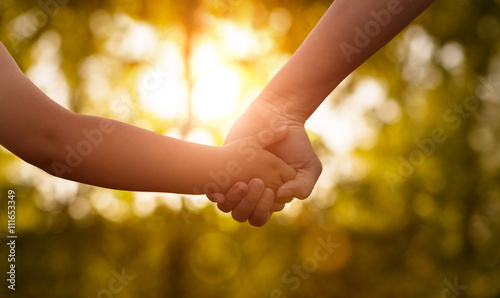 Fotografie Close up of mother or older sister and a child hands at the sunset