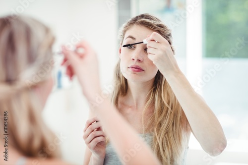 Young woman applying mascara photo