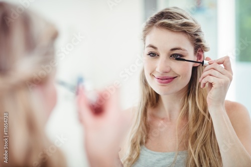 Smiling woman applying mascara