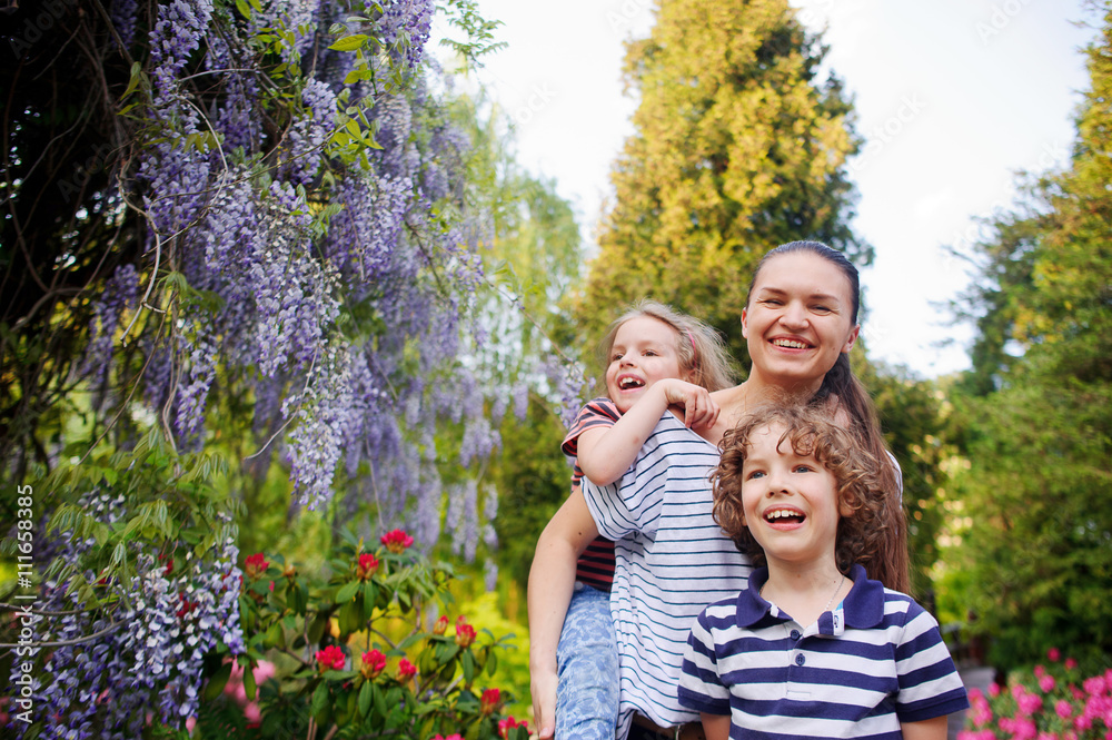 Fototapeta premium Mother with daughter and son walking in the summer park