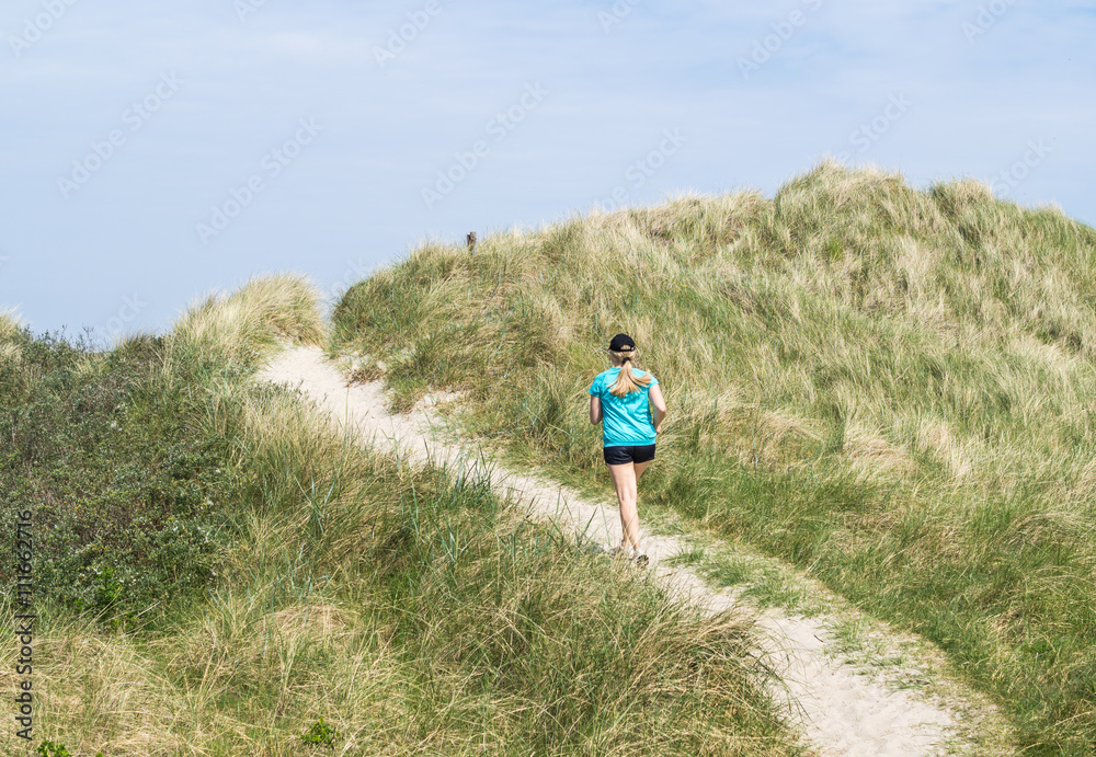 Frau joggt durch Dünen