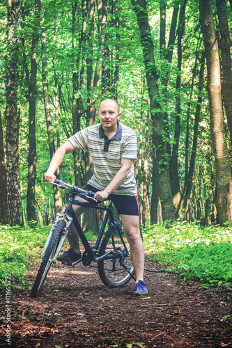 Young man, cyclist riding the bike, travels in the beautiful forest, summertime journey. Vintage effect