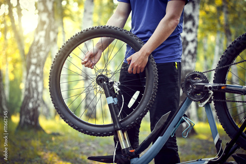 Man repairing a bike in the forest