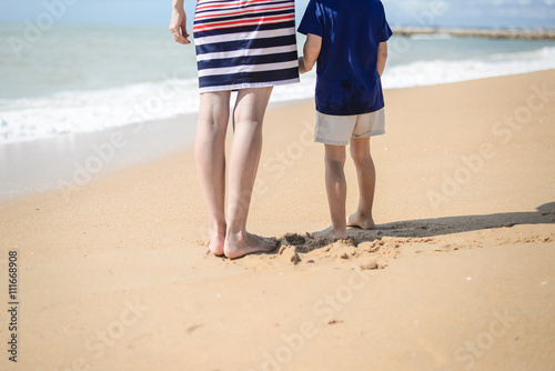 Back view of happy excited mother and kid have fun on beach on sunny outdoors  © gorosi