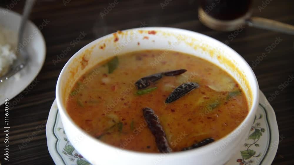 Asian man spoon the hot Thai spicy shrimp soup (Tom Yum Kung) from bowl with smoke Asian man spoon the hot Thai spicy shrimp soup (Tom Yum Kung) from bowl with smoke