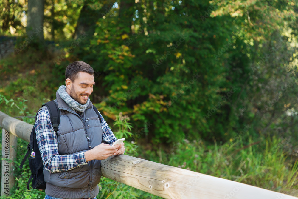 happy man with backpack and smartphone outdoors