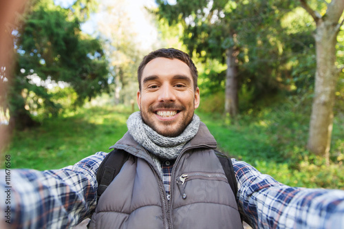 happy man with backpack taking selfie and hiking