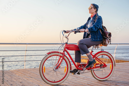 woman riding red vintage bicycle on seaside during sunset or sunrise 