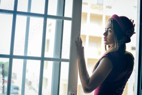 Side view photo of attractive stylish lady in red hat standing in doorway looking into distance