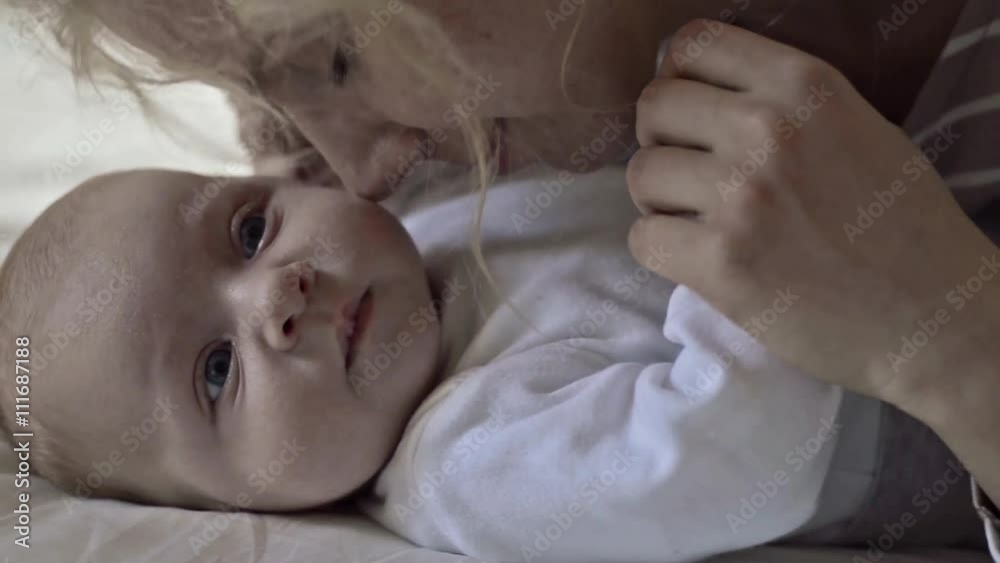 Baby boy lying on bed, held by his mother Baby boy lying on bed, held by his mother