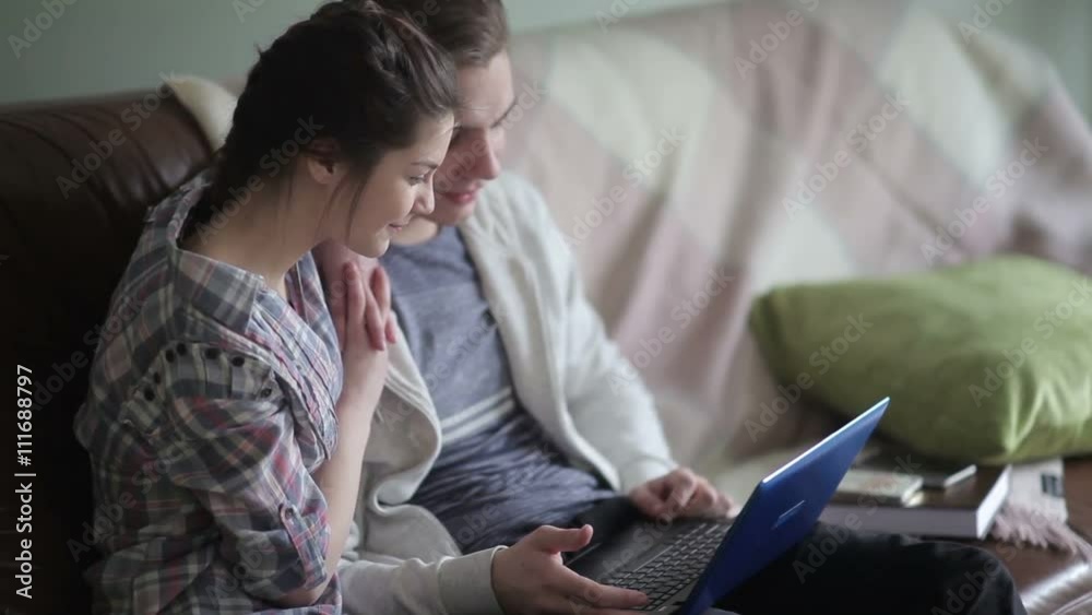Charming couple sits on the couch with a laptop. Charming couple sits on the couch with a laptop.