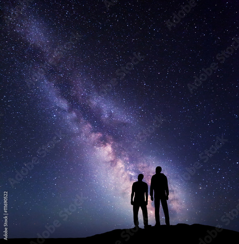 Silhouette of a family on the mountain. Father and a son on the background of Milky Way. Night landscape. Beautiful Universe. Space. Travel background with sky full of stars