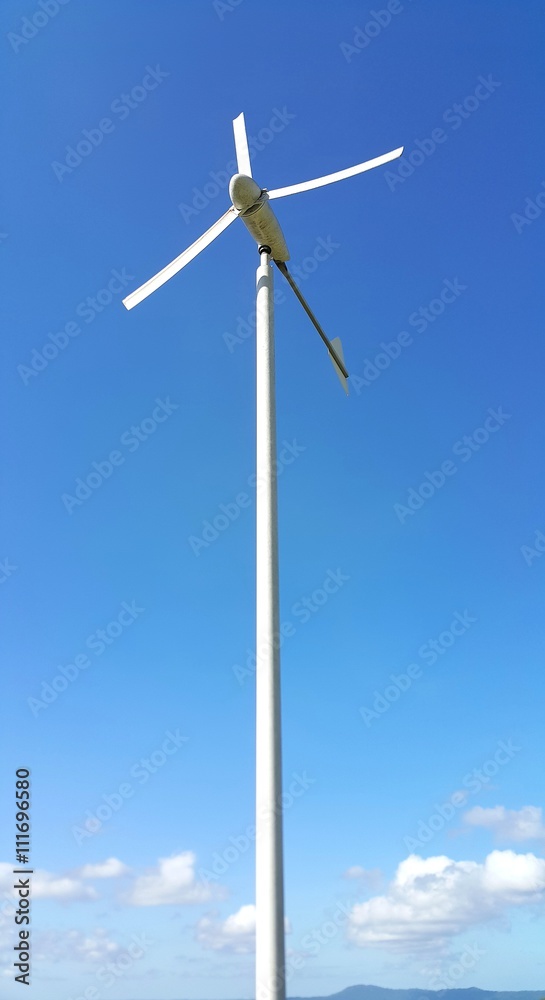 White water pumping wind mill on blue sky background White water pumping wind mill on blue sky background