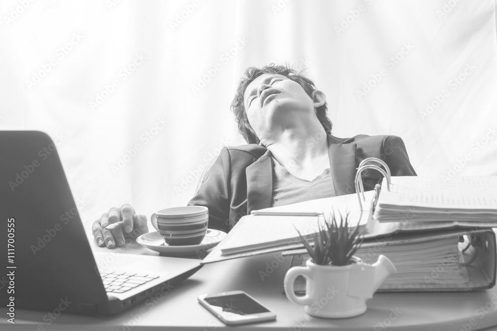 Businessman asleep at office desk with finance sheet and coffee.(concept for overworked) Businessman asleep at office desk with finance sheet and coffee.(concept for overworked)