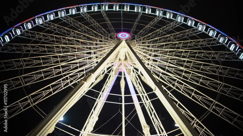 Gigantic Ferris wheel rotating slowly at theme park against back sky background photo