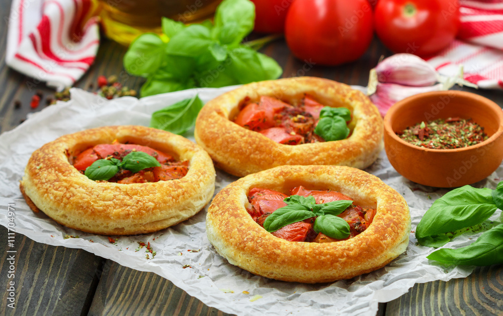 Homemade pie of puff pastry with tomatoes, Basil and spices. Mini round tomato tart. Rustic style
