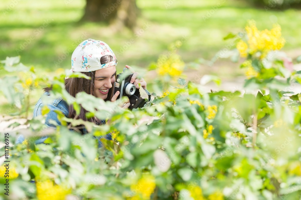 Portrait of a happy teeange girl taking photo with a vintage camera in a park