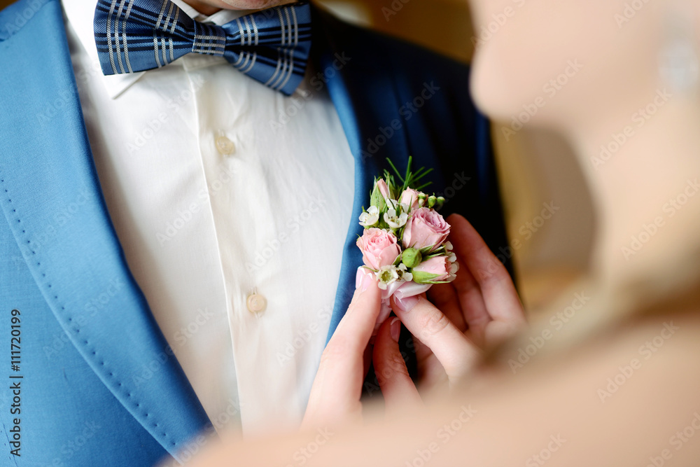 Groom and bride are wearing a boutonniere indoors. Male portrait of handsome guy. Beautiful model boy in colorful wedding clothes. Man is posing Groom and bride are wearing a boutonniere indoors. Male portrait of handsome guy. Beautiful model boy in colorful wedding clothes. Man is posing