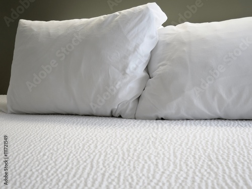 Detail of bed with set of white morning bedding 
