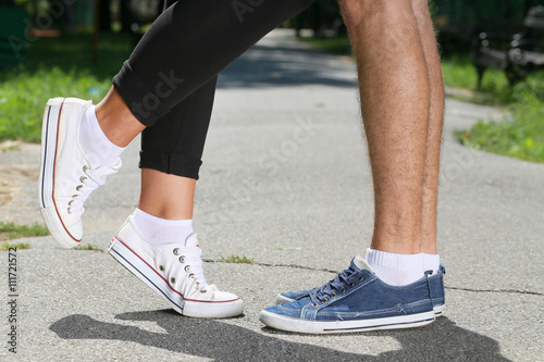 Male and female legs on pavement in a park