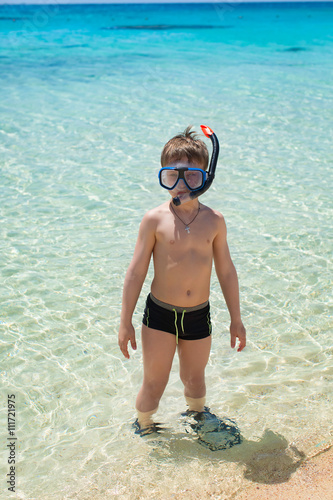 Joyful boy going to scuba diving in clear sea.