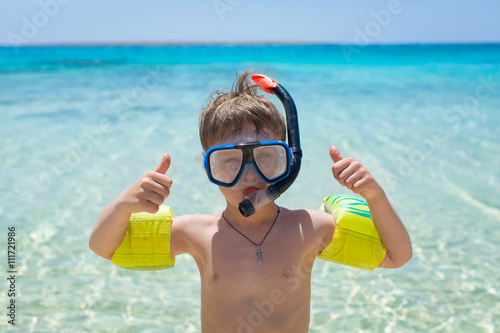 Joyful boy going to scuba diving in clear sea.