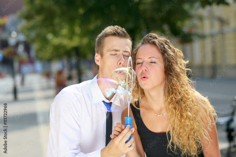 young couple blowing bubbles on walking street young couple blowing bubbles on walking street