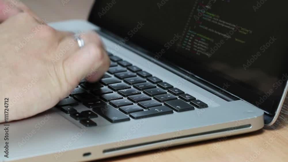 Closeup shot of a macbook laptop keyboard while a programmer types code into two editor windows, all logos covered Closeup shot of a macbook laptop keyboard while a programmer types code into two editor windows, all logos covered
